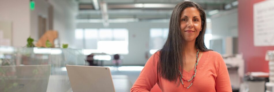 Mujer en la oficina posando orgullosa frente a la cámara. Foto de LinkedIn Sales Solutions en Unsplash