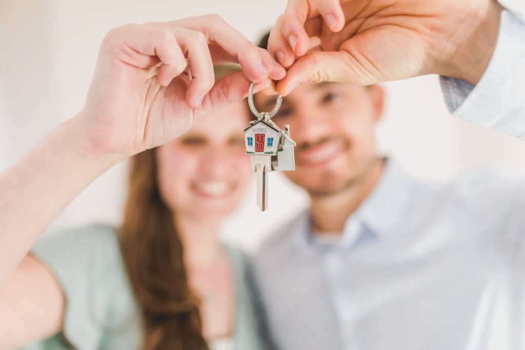 Pareja de recién casados mostrando con orgullo las llaves de su nueva casa